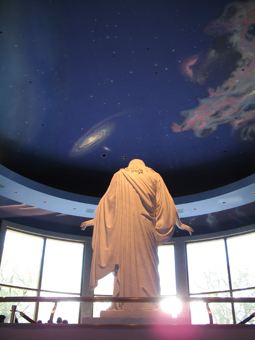 A statue of Jesus looks at followers below
