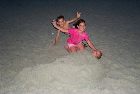 Paule and Pascal burying Erik in the sand on the beach