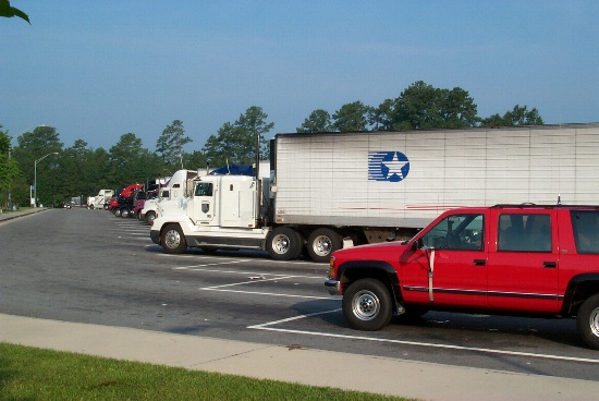 The little rig parked next to all the big rigs in the truck parking