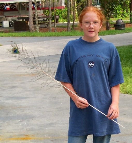 Isabella finds a long peacock feather near our trailer